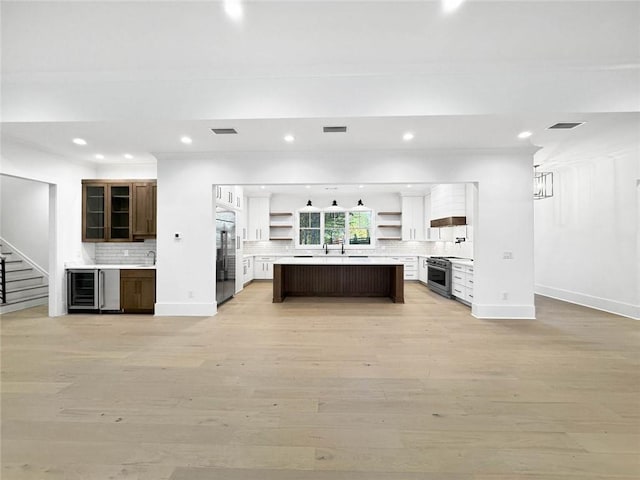 kitchen with a center island, stainless steel appliances, tasteful backsplash, light hardwood / wood-style flooring, and dark brown cabinets