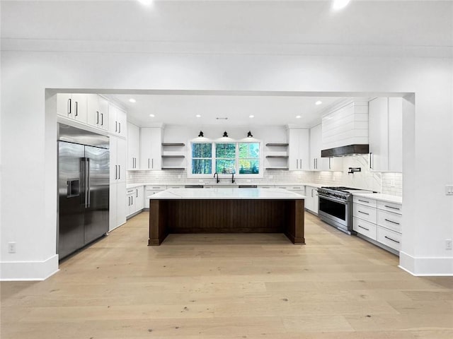 kitchen featuring light wood-type flooring, high quality appliances, a kitchen breakfast bar, a center island, and white cabinetry