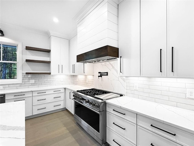 kitchen featuring high end range, custom exhaust hood, light stone countertops, backsplash, and white cabinets