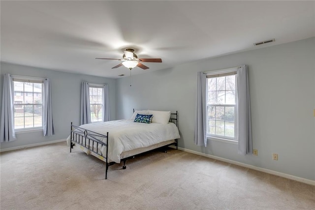 carpeted bedroom with a ceiling fan, visible vents, and baseboards