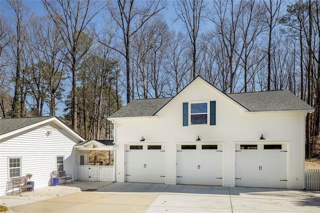 garage featuring driveway, a gate, and fence