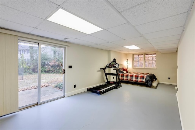 workout room featuring a paneled ceiling and baseboards