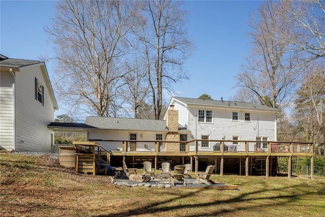 back of house featuring an outdoor fire pit, a chimney, a yard, and a deck