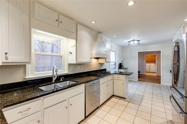 kitchen featuring light tile patterned floors, stainless steel appliances, a sink, independent washer and dryer, and custom exhaust hood