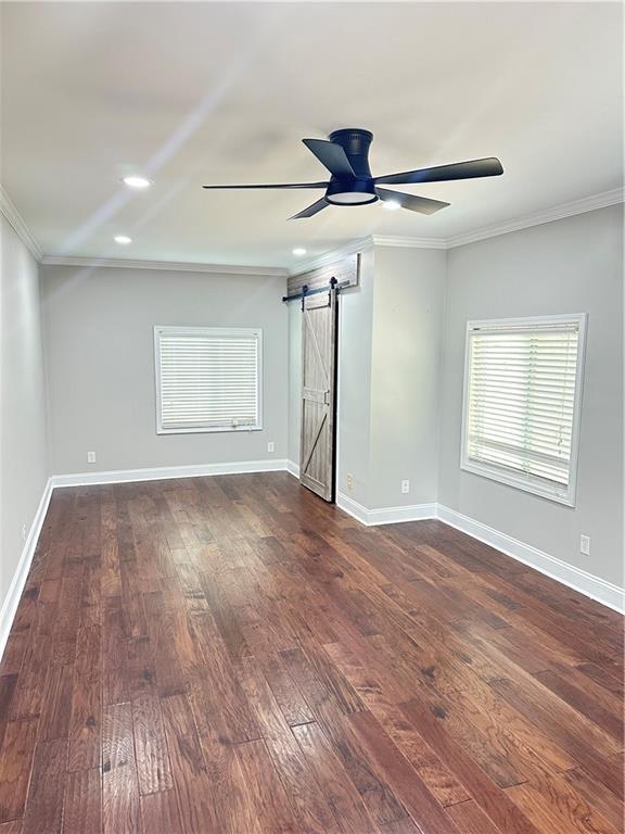 540 Langley Creek Dr, Loganville, GA 30052 - spare room with crown molding, a barn door, ceiling fan, dark wood-type flooring, and recessed lighting
