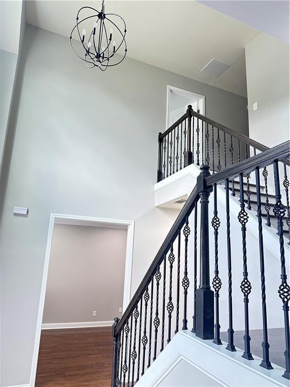 540 Langley Creek Dr, Loganville, GA 30052 - stairs featuring a chandelier, wood finished floors, and a high ceiling