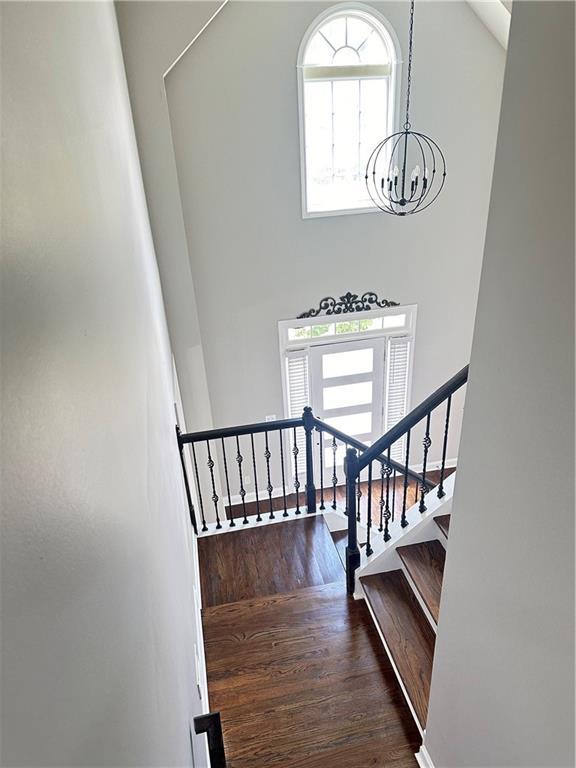 540 Langley Creek Dr, Loganville, GA 30052 - stairway featuring a high ceiling, wood finished floors, a chandelier, and healthy amount of natural light