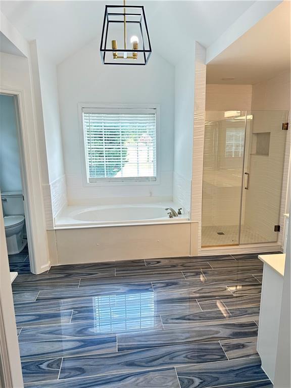 540 Langley Creek Dr, Loganville, GA 30052 - full bathroom with a bath, vanity, a stall shower, vaulted ceiling, and a chandelier