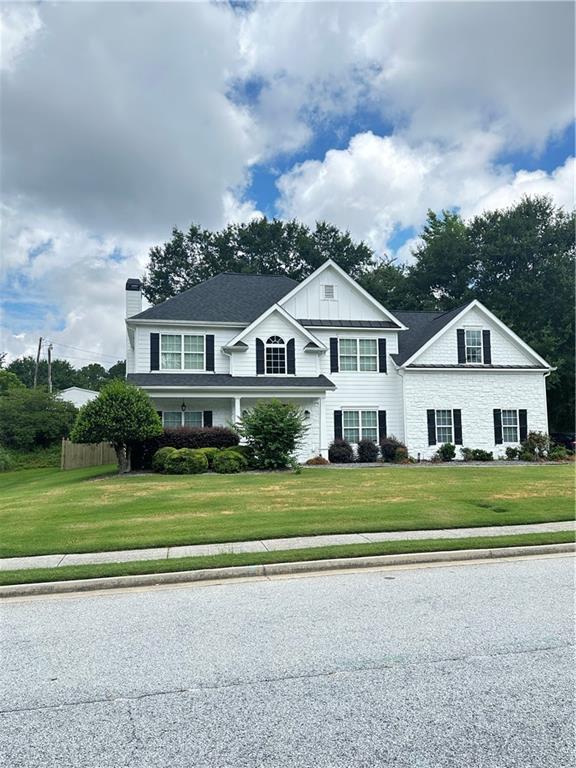 540 Langley Creek Dr, Loganville, GA 30052 - traditional-style house featuring a chimney, a front yard, board and batten siding, and stone siding