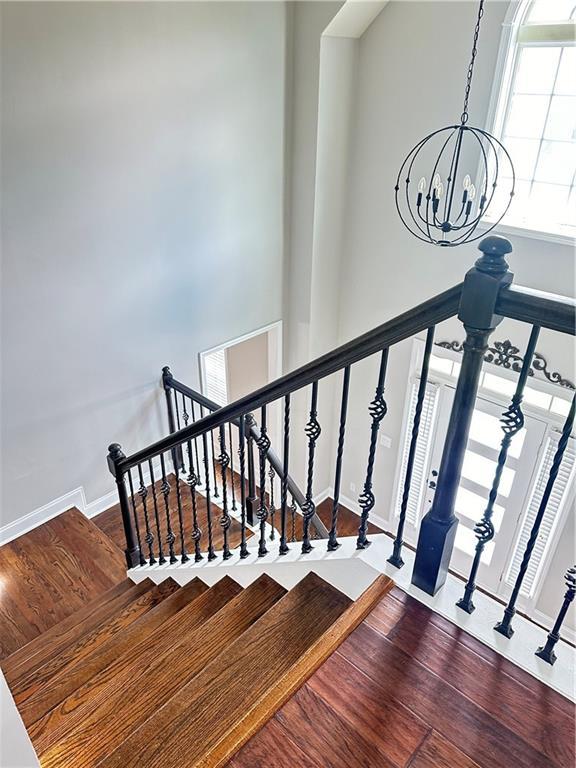 540 Langley Creek Dr, Loganville, GA 30052 - stairway featuring a chandelier and wood finished floors