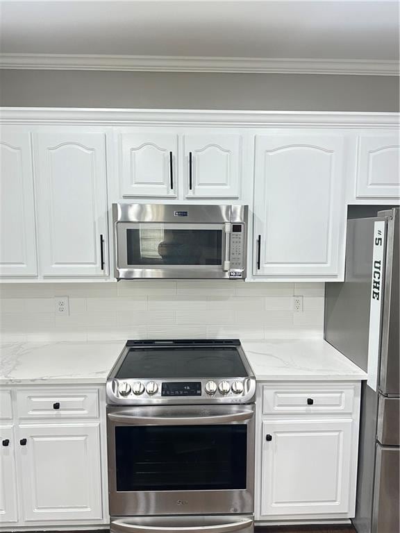 540 Langley Creek Dr, Loganville, GA 30052 - kitchen with appliances with stainless steel finishes, white cabinets, decorative backsplash, ornamental molding, and light stone countertops