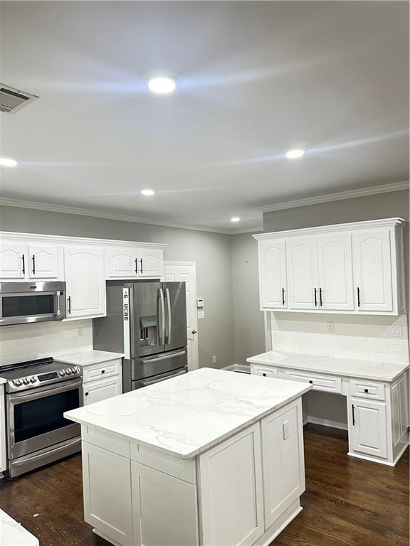 540 Langley Creek Dr, Loganville, GA 30052 - kitchen featuring stainless steel appliances, ornamental molding, white cabinets, light stone counters, and recessed lighting