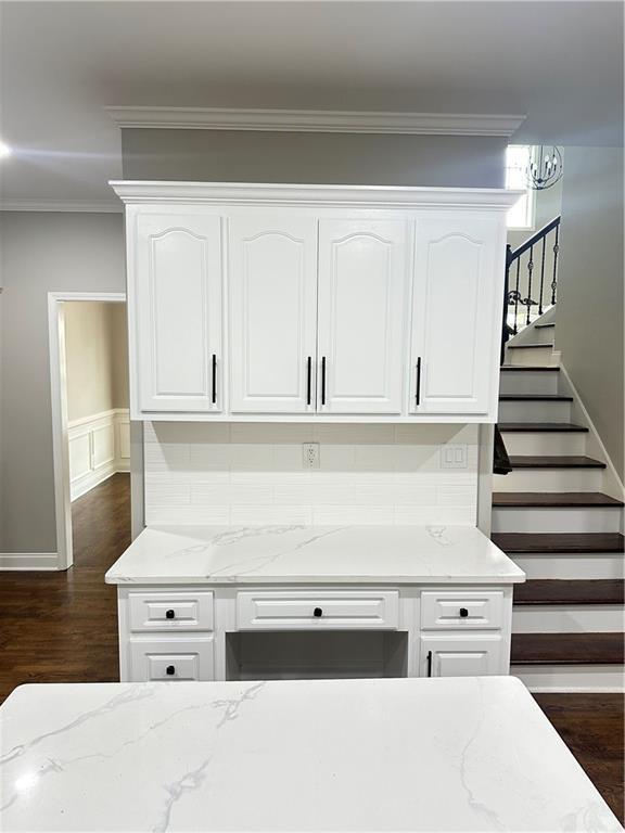 540 Langley Creek Dr, Loganville, GA 30052 - kitchen featuring light stone counters, crown molding, white cabinetry, and dark wood-style flooring