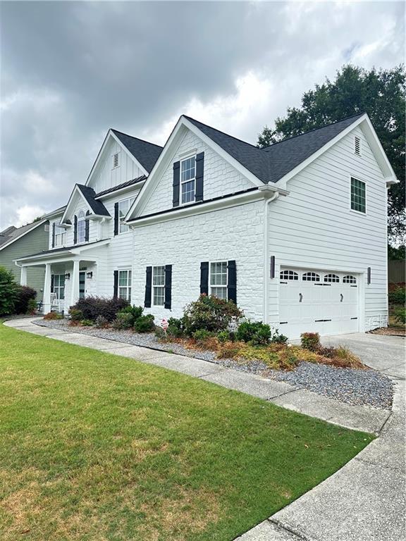 540 Langley Creek Dr, Loganville, GA 30052 - view of front facade featuring driveway, stone siding, a garage, a front lawn, and board and batten siding