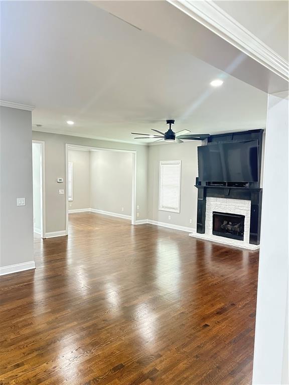540 Langley Creek Dr, Loganville, GA 30052 - unfurnished living room with ceiling fan, a fireplace, crown molding, wood finished floors, and recessed lighting