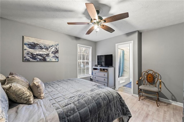 bedroom featuring light wood finished floors, baseboards, ceiling fan, ensuite bathroom, and a textured ceiling