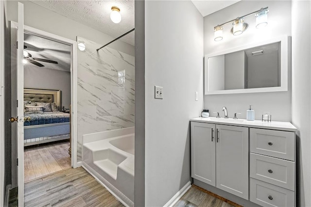 full bath with a tub to relax in, wood finished floors, walk in shower, a textured ceiling, and vanity