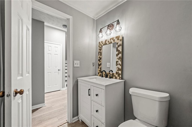 half bathroom featuring toilet, baseboards, wood finished floors, and vanity