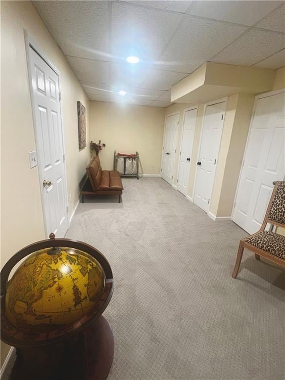 living area with a drop ceiling, carpet flooring, and baseboards