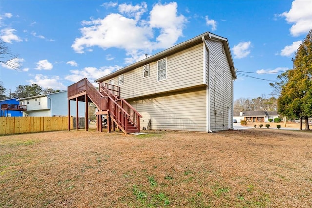 rear view of property featuring a yard, fence, stairway, and a deck