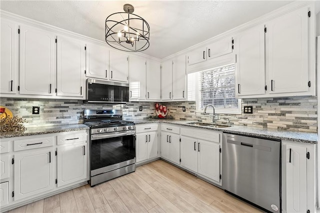 kitchen with backsplash, light wood-style flooring, appliances with stainless steel finishes, white cabinets, and a sink