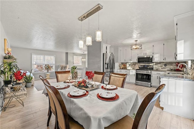 dining space with a textured ceiling and light wood-style floors