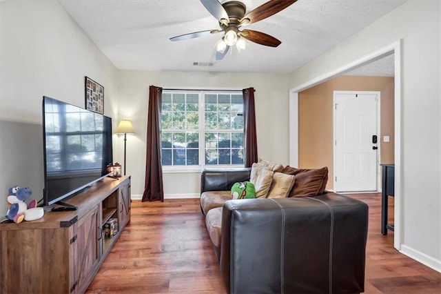 living room with dark wood-type flooring, a textured ceiling, and ceiling fan