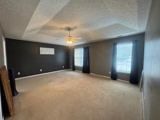 carpeted spare room featuring ceiling fan and a tray ceiling