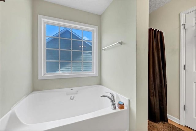 bathroom with a textured ceiling and a tub to relax in