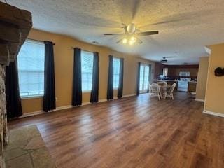 unfurnished living room featuring plenty of natural light, dark hardwood / wood-style floors, and ceiling fan