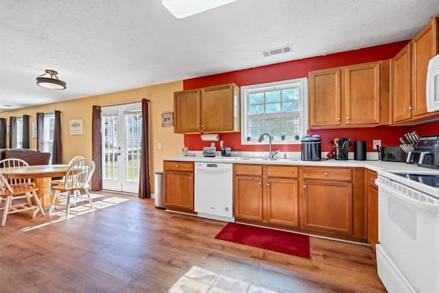 kitchen with sink, white appliances, light hardwood / wood-style flooring, and a wealth of natural light