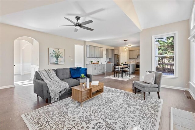 living area featuring a fireplace, a ceiling fan, vaulted ceiling, wood finished floors, and baseboards