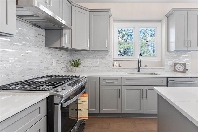 kitchen featuring stainless steel appliances, decorative backsplash, a sink, light stone countertops, and under cabinet range hood