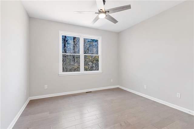 empty room featuring ceiling fan, baseboards, and wood finished floors