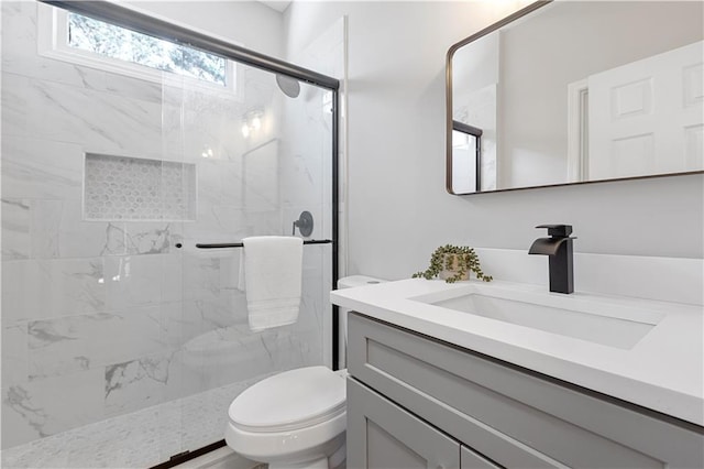 full bath featuring a marble finish shower, vanity, and toilet