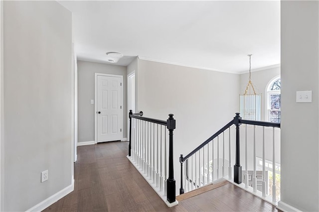 corridor featuring ornamental molding, baseboards, an upstairs landing, and wood finished floors