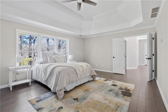 bedroom with baseboards, ornamental molding, dark wood finished floors, and a raised ceiling