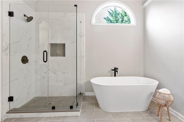 full bathroom with a soaking tub, a marble finish shower, and baseboards