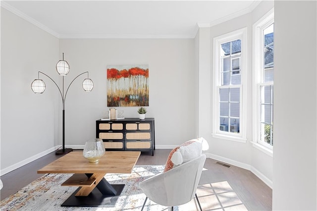 living area with ornamental molding, wood finished floors, visible vents, and baseboards