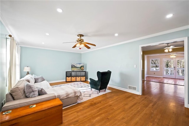 living area with baseboards, wood finished floors, visible vents, and crown molding