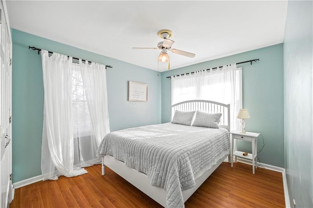 bedroom with a ceiling fan, baseboards, and wood finished floors