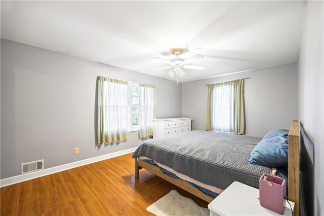 bedroom with wood finished floors, visible vents, and multiple windows