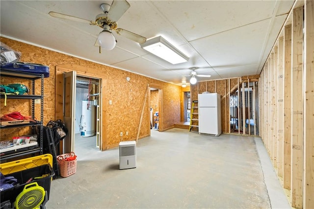 basement featuring water heater, a ceiling fan, and freestanding refrigerator