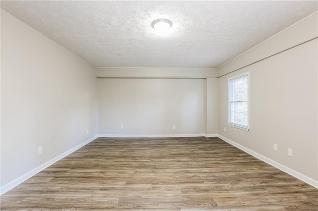 spare room with a textured ceiling and hardwood / wood-style flooring