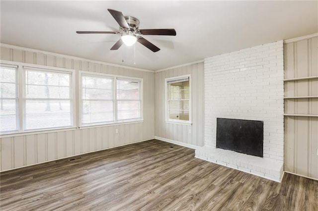 unfurnished living room featuring ceiling fan, ornamental molding, dark wood-type flooring, and a brick fireplace