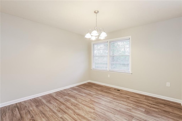 empty room with light hardwood / wood-style flooring and a notable chandelier