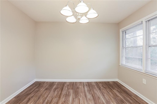 spare room with wood-type flooring and a chandelier