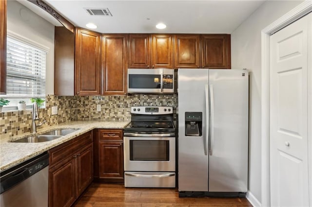 kitchen featuring visible vents, a sink, backsplash, stainless steel appliances, and dark wood-style flooring