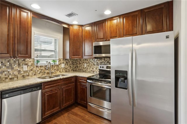 kitchen with a sink, visible vents, light stone countertops, and appliances with stainless steel finishes