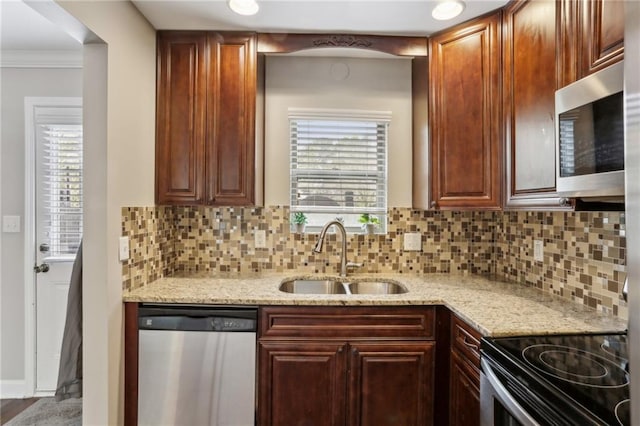 kitchen with ornamental molding, light stone counters, decorative backsplash, stainless steel appliances, and a sink